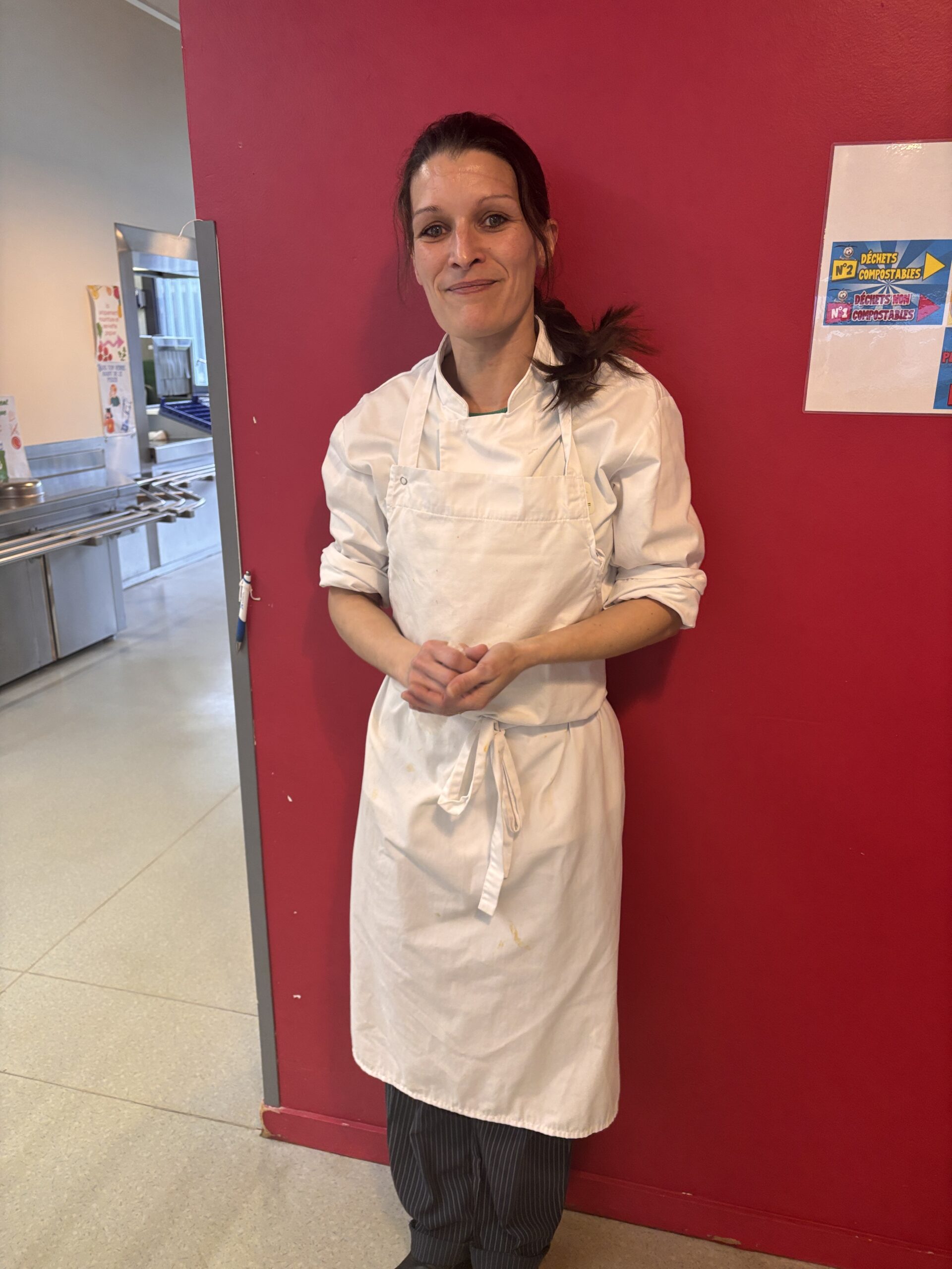 Seconde de cuisine en tenue devant mur rose